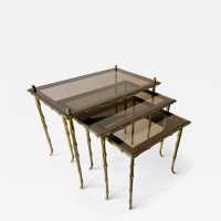 Set of three bamboo nesting or stacking tables, Mid-Century Modern style, in gilded bronze with smoked glass top, by the French manufacturer Maison Baguès. Famous houses such as Maison Jansen, Roger Robert Thibier, Charles, Ramsey and Romeo Rega were also represented.