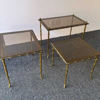 Set of three bamboo nesting or stacking tables, Mid-Century Modern style, in gilded bronze with smoked glass top, by the French manufacturer Maison Baguès. Famous houses such as Maison Jansen, Roger Robert Thibier, Charles, Ramsey and Romeo Rega were also represented.