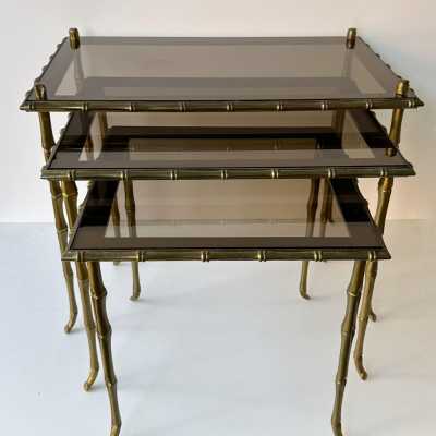 Set of three bamboo nesting or stacking tables, Mid-Century Modern style, in gilded bronze with smoked glass top, by the French manufacturer Maison Baguès. Famous houses such as Maison Jansen, Roger Robert Thibier, Charles, Ramsey and Romeo Rega were also represented.