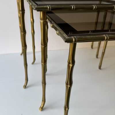 Set of three bamboo nesting or stacking tables, Mid-Century Modern style, in gilded bronze with smoked glass top, by the French manufacturer Maison Baguès. Famous houses such as Maison Jansen, Roger Robert Thibier, Charles, Ramsey and Romeo Rega were also represented.