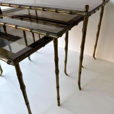 Set of three bamboo nesting or stacking tables, Mid-Century Modern style, in gilded bronze with smoked glass top, by the French manufacturer Maison Baguès. Famous houses such as Maison Jansen, Roger Robert Thibier, Charles, Ramsey and Romeo Rega were also represented.