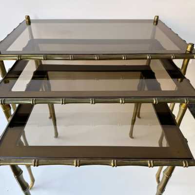 Set of three bamboo nesting or stacking tables, Mid-Century Modern style, in gilded bronze with smoked glass top, by the French manufacturer Maison Baguès. Famous houses such as Maison Jansen, Roger Robert Thibier, Charles, Ramsey and Romeo Rega were also represented.